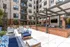 Courtyard lounge at Auburn student apartments. Vibrant open-air patio with modern seating, string lights, and a stylish barbecue area at a contemporary apartment complex.