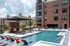 Poolside seating area at Auburn student apartments. Modern apartment complex showcasing a luxurious outdoor pool with stylish lounge chairs, surrounded by elegant brick architecture and shaded seating areas.