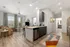 Open floorplan Living room in Auburn student apartment near campus. Bright and modern open-concept apartment featuring a cozy living area with a chic brown couch, stylish kitchen with sleek cabinetry, and vibrant geometric rug, bathed in natural light from large windows.