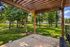 Grounds with mature trees and shaded patio with bench at Urban Oaks | Conroe, TX Apartments