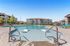 Relaxing outdoor pool area at a modern apartment complex with sun loungers and elegant buildings in the background.