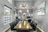 A sleek modern dining room with stylish lighting and integrated workspace, featuring a large window and tasteful decor.