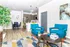 Open-concept living room with vibrant blue chairs, modern kitchen, and dining area.