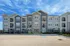 Elegant three-story apartment building with balconies and modern design under a clear blue sky.
