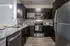 Contemporary kitchen with stainless steel appliances, dark wood cabinets, and marble countertops.