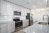 Modern kitchen with sleek granite countertops, stainless steel appliances, and elegant white cabinetry, featuring a stylish faucet and chic lighting.