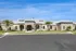 Elegant residential building with stone fa&ccedil;ade, arched windows, and lush landscaping under a vibrant blue sky.