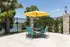 Inviting outdoor patio with vibrant yellow umbrella, turquoise chairs, and scenic lake views.