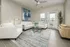 Bright and inviting living room with modern decor, elegant beige sofas, vibrant artwork, and large windows for natural light.