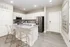 Sleek modern kitchen boasting white cabinetry, granite countertops, and stylish transparent bar stools on elegant wood flooring.