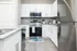 Sleek modern kitchen with stainless steel appliances, white cabinetry, and granite countertops.