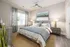 Elegant bedroom with a plush bed, stylish artwork, and ample natural light creating a serene retreat.