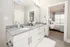 Modern bathroom with elegant granite countertop and double sinks, leading to a cozy bedroom with large windows.