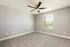 Bright, spacious bedroom with plush carpet, ceiling fan, and large window offering serene outdoor views.