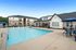 Inviting outdoor pool area with modern apartment buildings in the background, featuring poolside seating and shaded areas for relaxation.
