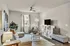 Inviting living room with modern decor, featuring a cozy beige sectional, stylish wall art, and abundant natural light.