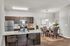 Modern open-plan kitchen and dining area with elegant dark wood cabinets, granite countertops, and contemporary decor.