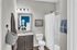 Bright and modern bathroom with granite countertop, elegant fixtures, and a glimpse of a cozy bedroom with stylish decor.