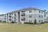Modern three-story apartment building with private balconies and lush landscaping, set in a serene neighborhood.
