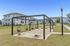 Inviting apartment complex exterior with modern swings on a lush green lawn, offering a perfect outdoor relaxation space.