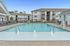 Inviting apartment complex featuring a sparkling swimming pool surrounded by lounge chairs, perfect for relaxation and leisure.