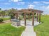 Inviting outdoor grilling area with wooden pergola and lush green surroundings, perfect for gatherings under the blue sky.