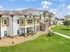 Charming apartment complex featuring modern architecture, lush green lawns, and sunlit balconies perfect for relaxation.