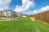 Spacious apartment community with modern three-story buildings, lush green lawns, and clear blue skies, offering a serene living environment.