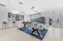Inviting recreational space with a modern pool table on a plush blue rug, framed by stylish bar stools and artful wall decor.