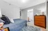 Inviting bedroom with a cozy blue bedding, wooden dresser, and a stylishly decorated bathroom, showcasing modern apartment elegance.