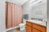 Bright and inviting bathroom with a warm wood vanity, modern fixtures, and a stylish pink shower curtain.