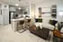 Modern open-concept living room and kitchen with elegant decor, featuring a cozy seating area, stylish artwork, and a sleek kitchen island with stainless steel appliances.
