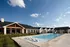 Stunning outdoor area featuring a sparkling swimming pool, modern sun loungers, and elegant clubhouse under a clear blue sky.