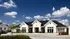 Charming modern bungalow with stone facade and lush landscaping under a clear blue sky.