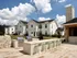 Charming residential apartment complex with modern grilling area and inviting outdoor seating, set against a bright, sunny day with picturesque clouds.