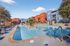 Vibrant apartment complex with a refreshing outdoor pool, colorful modern architecture, and inviting poolside seating in a sunny setting.