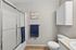 Elegant bathroom with modern tiled floor, glass shower enclosure, and sleek white cabinetry, accented by tasteful artwork and deep blue towels.