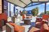 Inviting outdoor patio area featuring elegant wicker furniture with orange cushions, a stone barbecue grill, and a sparkling pool, ideal for relaxation and entertaining.
