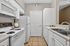 Bright, modern kitchen with sleek white cabinets, tiled floor, and stainless steel sink, offering a stylish and functional layout.