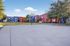 Colorful apartment complex exterior featuring vibrant red and blue buildings, lush green lawns, and a community basketball court under a clear blue sky.