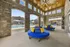 Charming outdoor lounge area with vibrant blue seating and colorful pillows, overlooking a sparkling pool and stylish stone architecture.