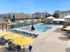 Luxury apartment complex with a sparkling outdoor pool, surrounded by blue sun loungers and vibrant yellow umbrellas, perfect for relaxation and leisure.