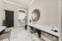 Elegant home office with a large wall clock and modern decor, featuring sleek marble flooring and ample natural light from a picturesque window.