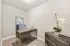 Modern home office with sleek desk and decorative accents, featuring a geometric mirror and a vibrant orchid on wood flooring.