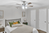 Inviting bedroom featuring a cozy bed with stylish pillows, modern ceiling fan, and elegant bedside tables.