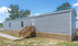 Charming mobile home showcasing a sleek exterior with a welcoming wooden staircase and a peaceful natural backdrop.