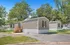 Charming mobile home surrounded by lush trees, featuring a welcoming front porch and ample parking space.
