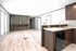 Modern, spacious apartment interior showcasing sleek kitchen cabinetry, elegant wood finishes, and an open living area with abundant natural light.