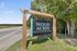 Inviting sign for Wood Acres Manufactured Homes surrounded by lush greenery and a peaceful roadside setting.