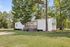 Charming mobile home nestled among lush trees, featuring a cozy porch and spacious green lawn.